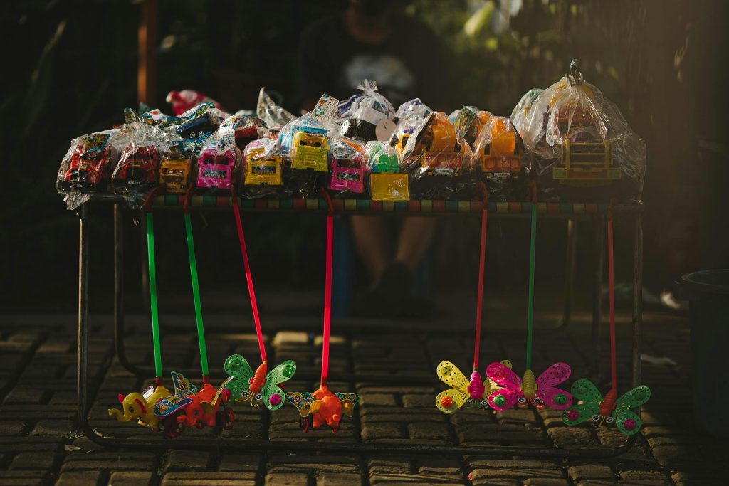 A vibrant street display of various colorful toys packaged and arranged on a market stall.