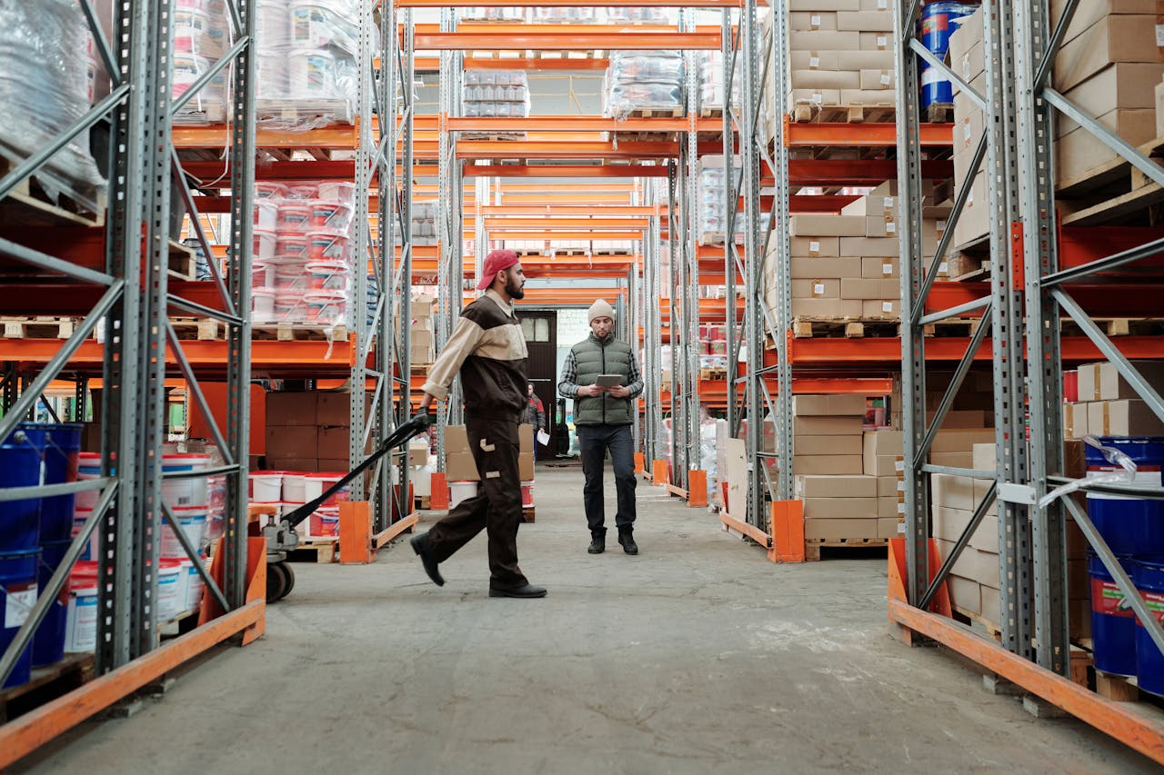 our-experience Two workers manage inventory in a spacious warehouse aisle.